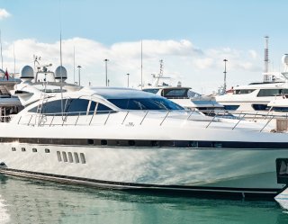 White and black yacht tied up in marina with other boats