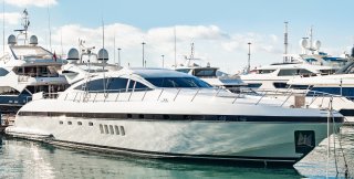 White and black yacht tied up in marina with other boats